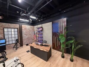 Podcast video studio with multiple sets, brick wall, wood desk and studio lighting